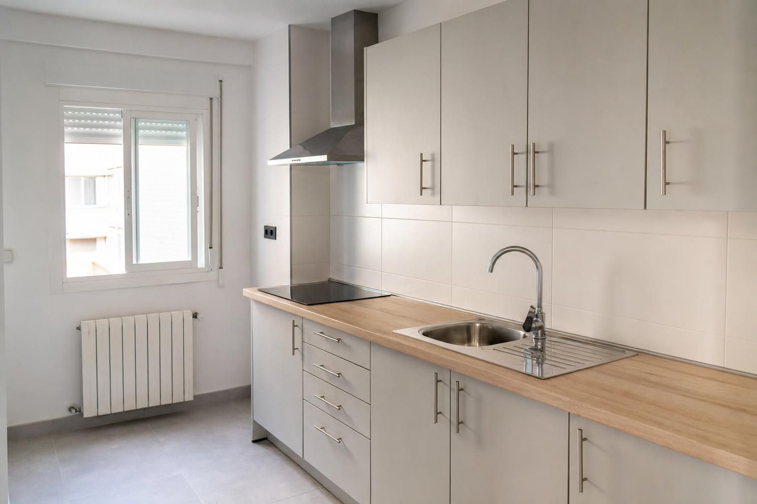 Cocina reformada con muebles blancos, encimera laminada imitación madera y placa de inducción